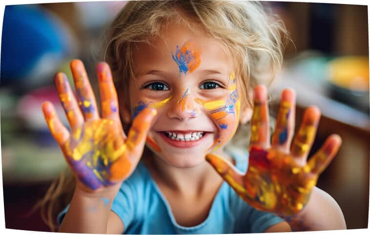Happy child showing their hands with colorful paint during a physiotherapy session.